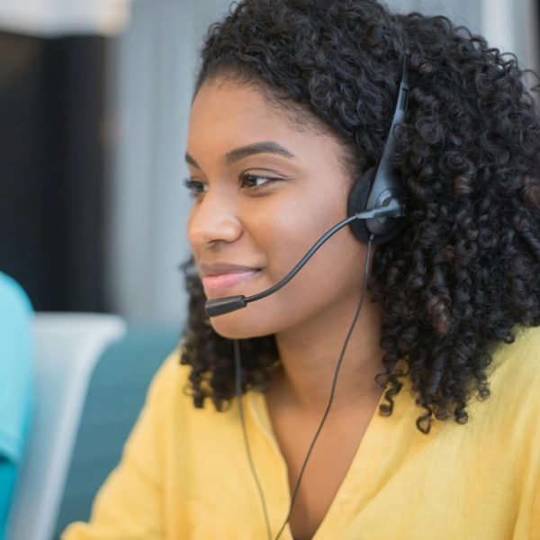 Focused call center agent with curly hair in a yellow blouse providing customer support.